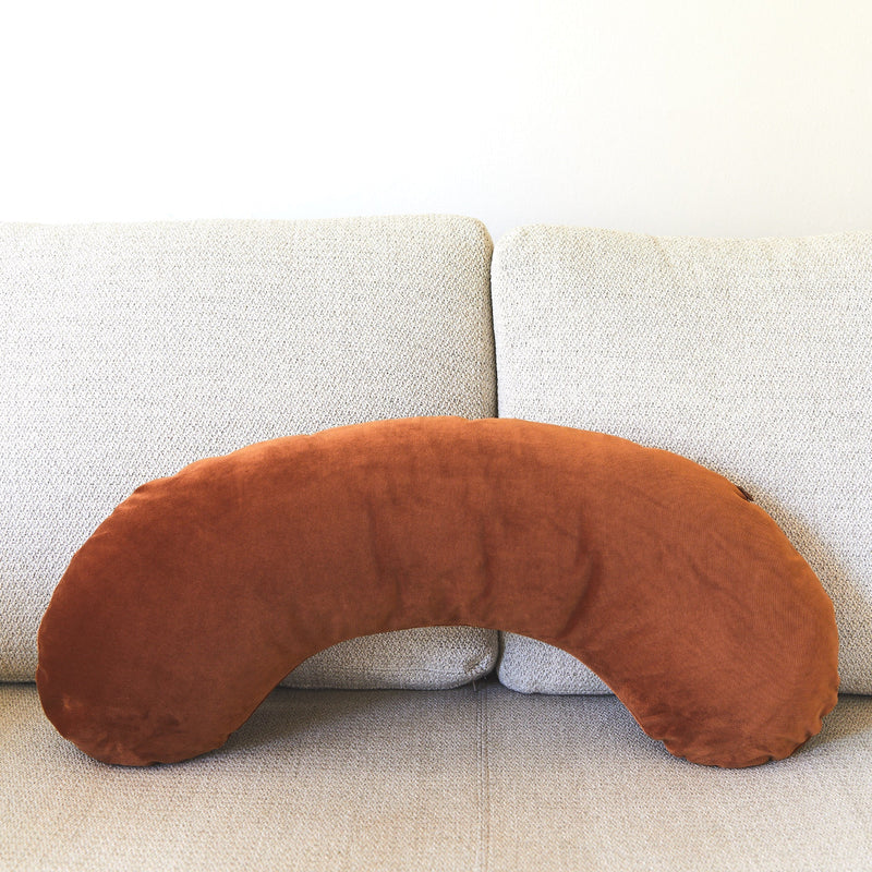 Brown U-shaped pillow on a light gray sofa