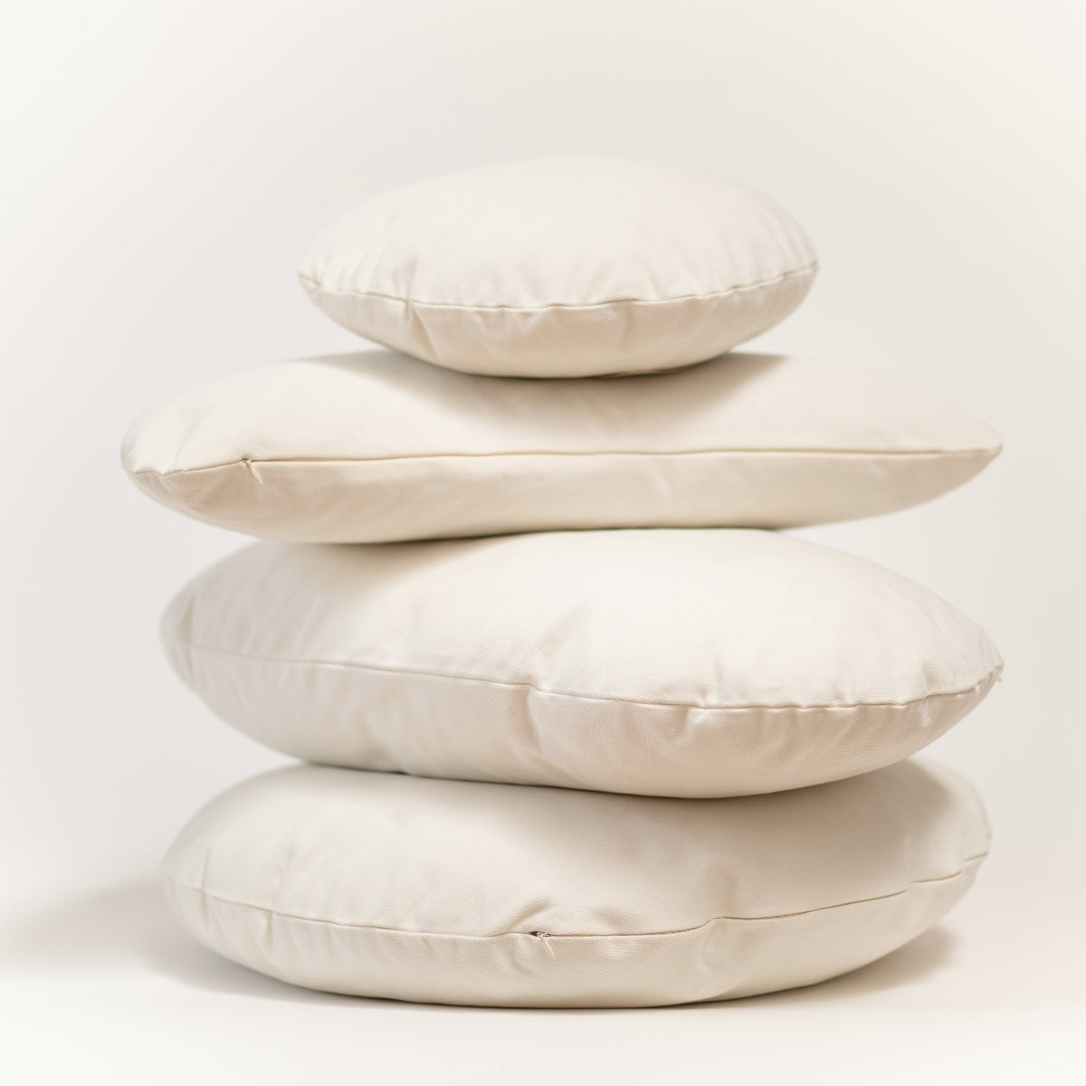 Stack of beige cushions on a light background