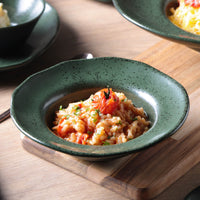 Green ceramic bowl with a dish of food on a wooden surface