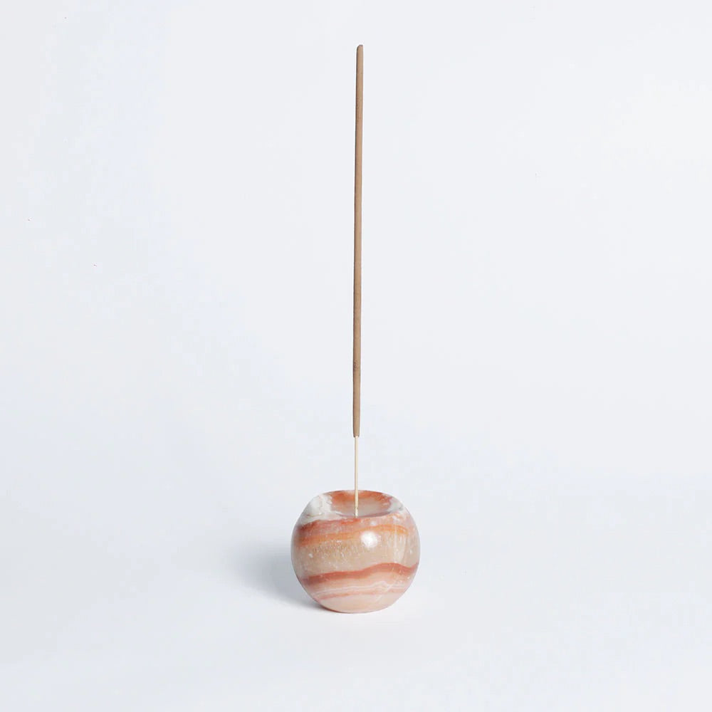 Incense stick in a marbled stone holder on a light gray background