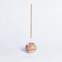 Incense stick in a marbled stone holder on a light gray background