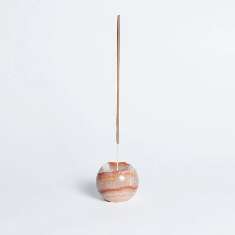 Incense stick in a marbled stone holder on a light gray background