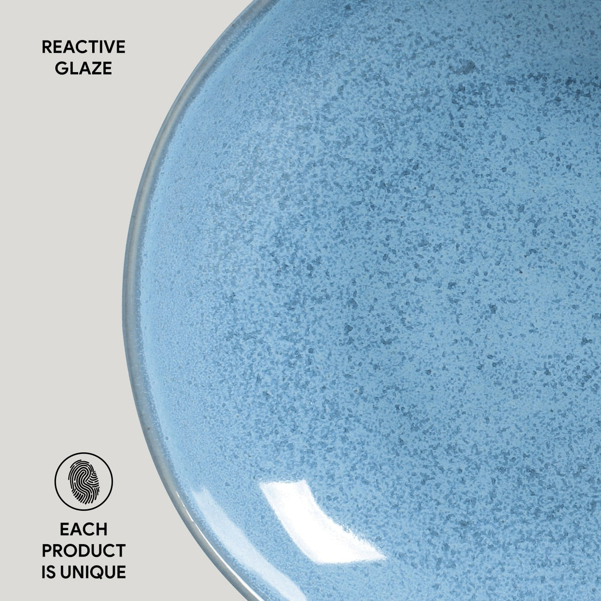 Close-up of a blue ceramic plate with reactive glaze texture on a light gray background.