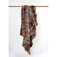 Plaid blanket draped over a wooden rod on a white background