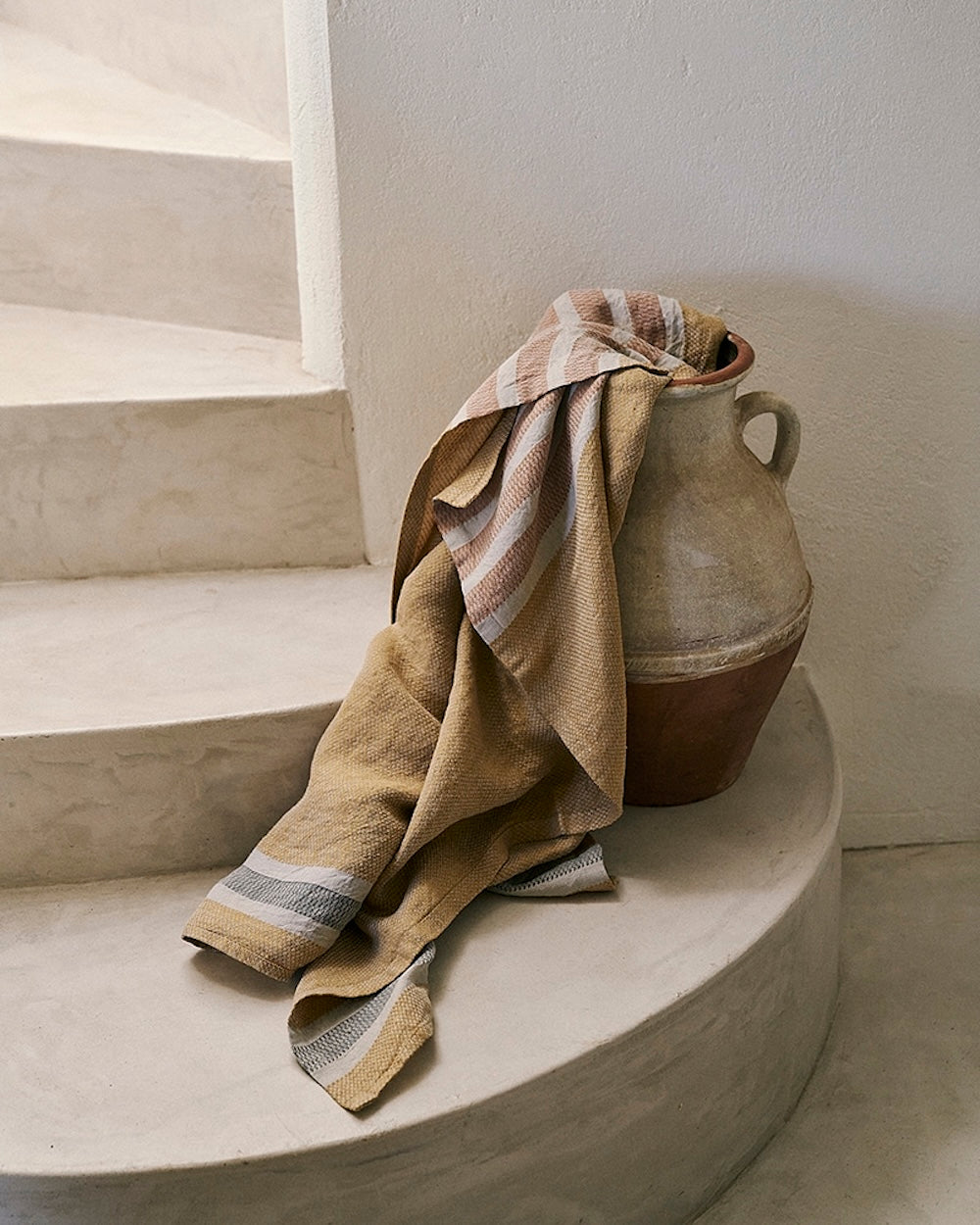 Towel draped over a ceramic vase on a staircase