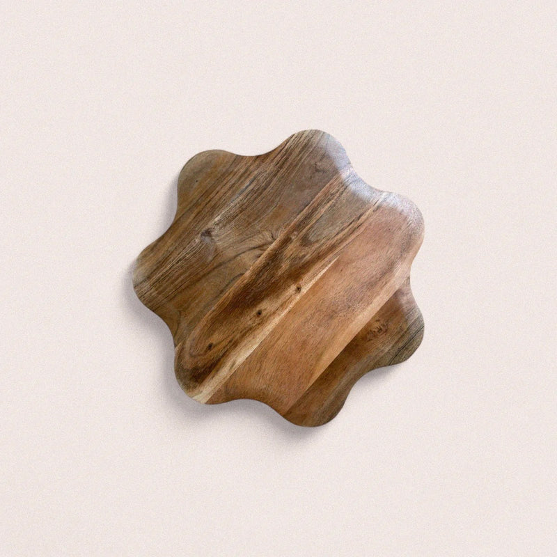 Wooden serving board with wavy edges on a light beige background