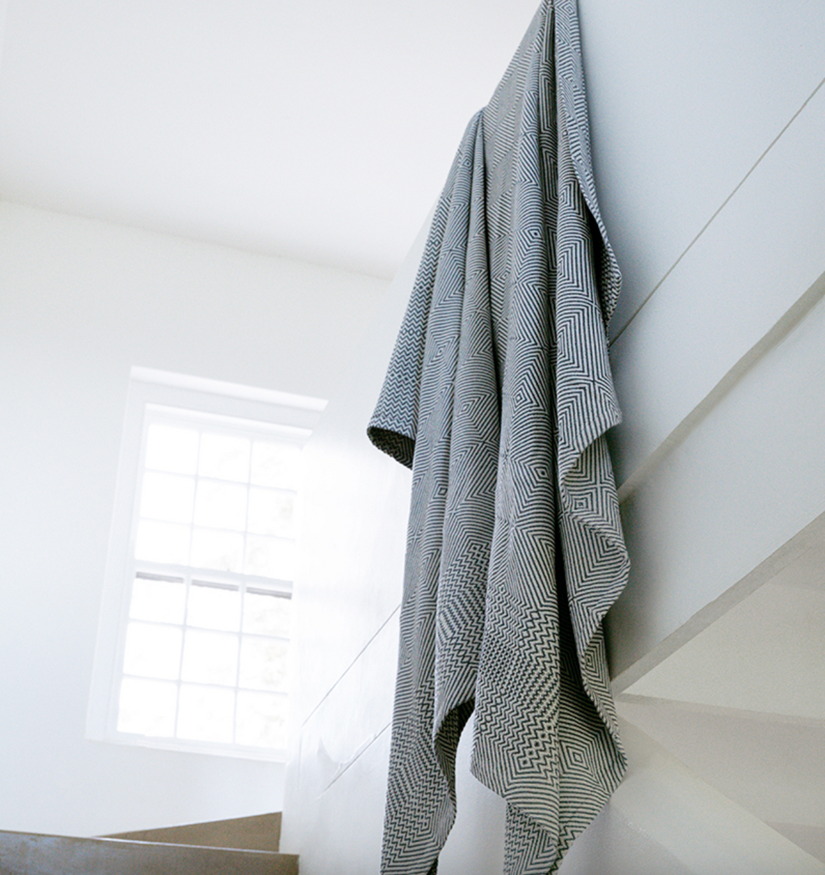 Gray textured blanket hanging on a white wall