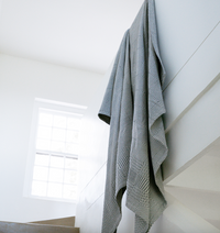 Gray textured blanket hanging on a white wall