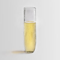Pebbled glass stemless flute filled with champagne on a white background