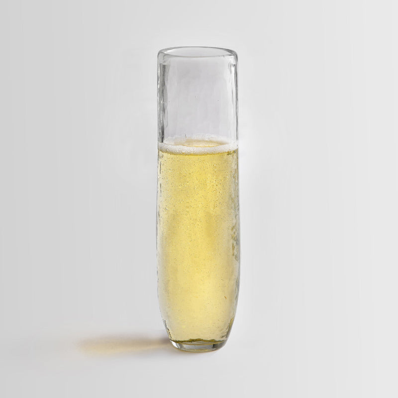 Pebbled glass stemless flute filled with champagne on a white background