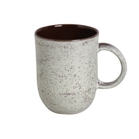 Speckled ceramic mug with a brown interior on a white background