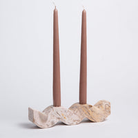 Stone candle holder with two mauve taper candles on a light gray background