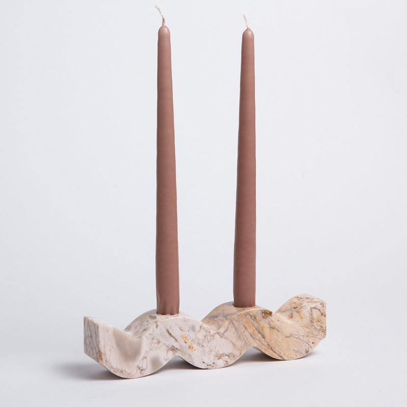 Stone candle holder with two mauve taper candles on a light gray background