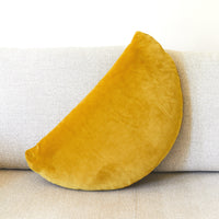 Mustard yellow crescent-shaped pillow on a light gray sofa