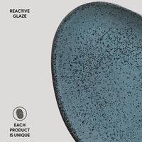 Blue ceramic plate with speckled glaze on a light gray background