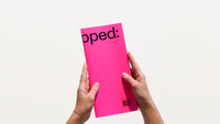 Person holding a pink magazine titled 'Untapped' on a white background