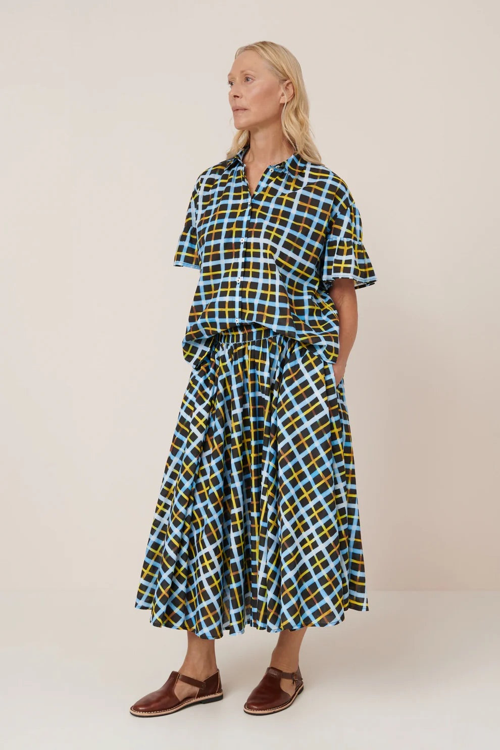 Woman wearing a checkered shirt and skirt with a plain background