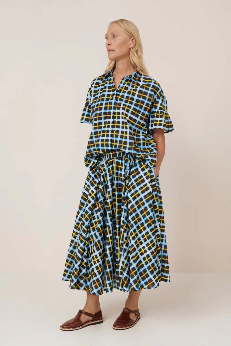 Woman wearing a checkered shirt and skirt with a plain background