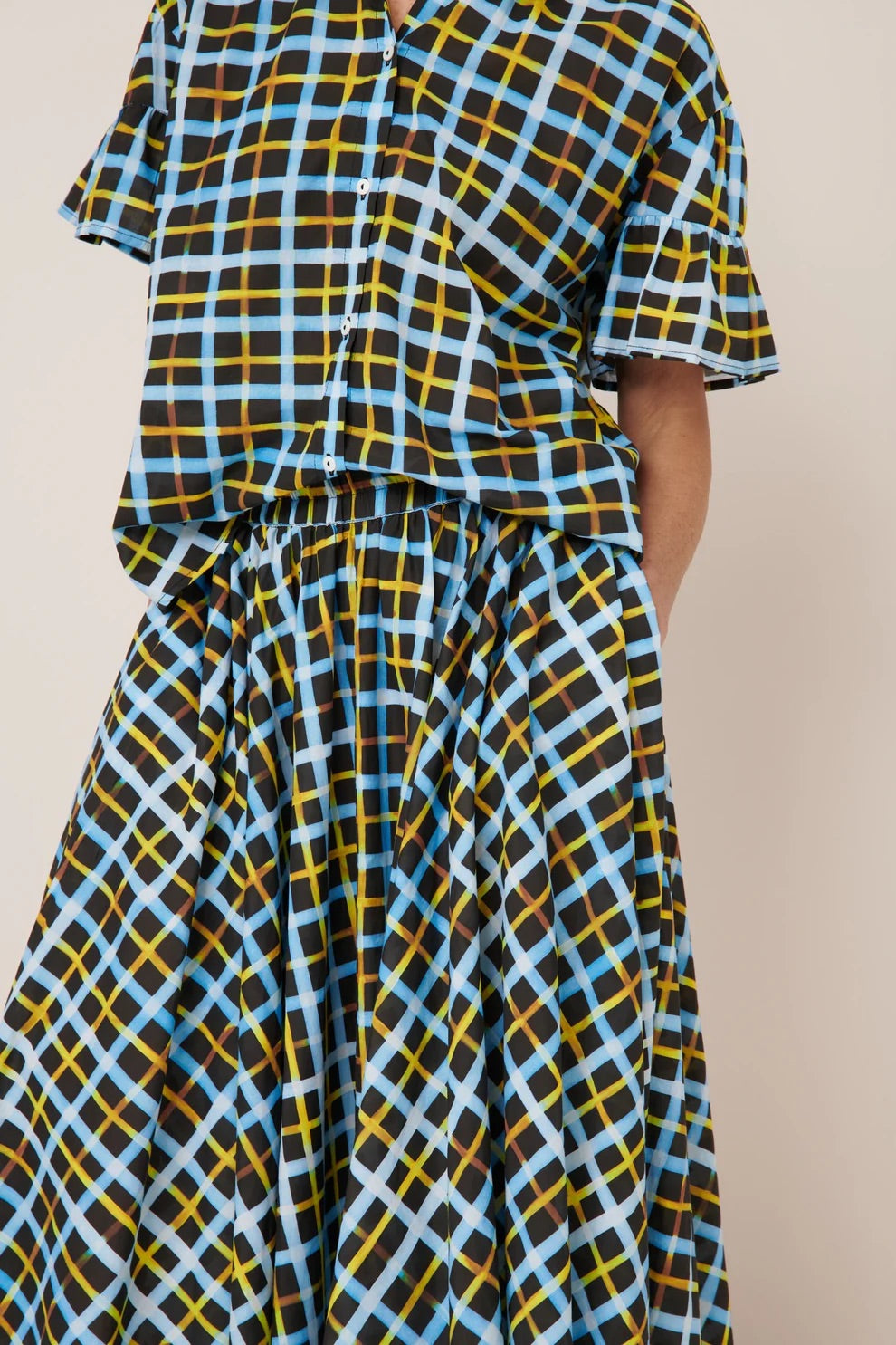 Plaid shirt and skirt with blue, yellow, and black pattern on a beige background