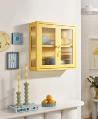 Yellow glass-front cabinet on a white wall with decorative items below.