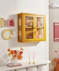 Yellow glass-front cabinet on a white wall with decorative items below.