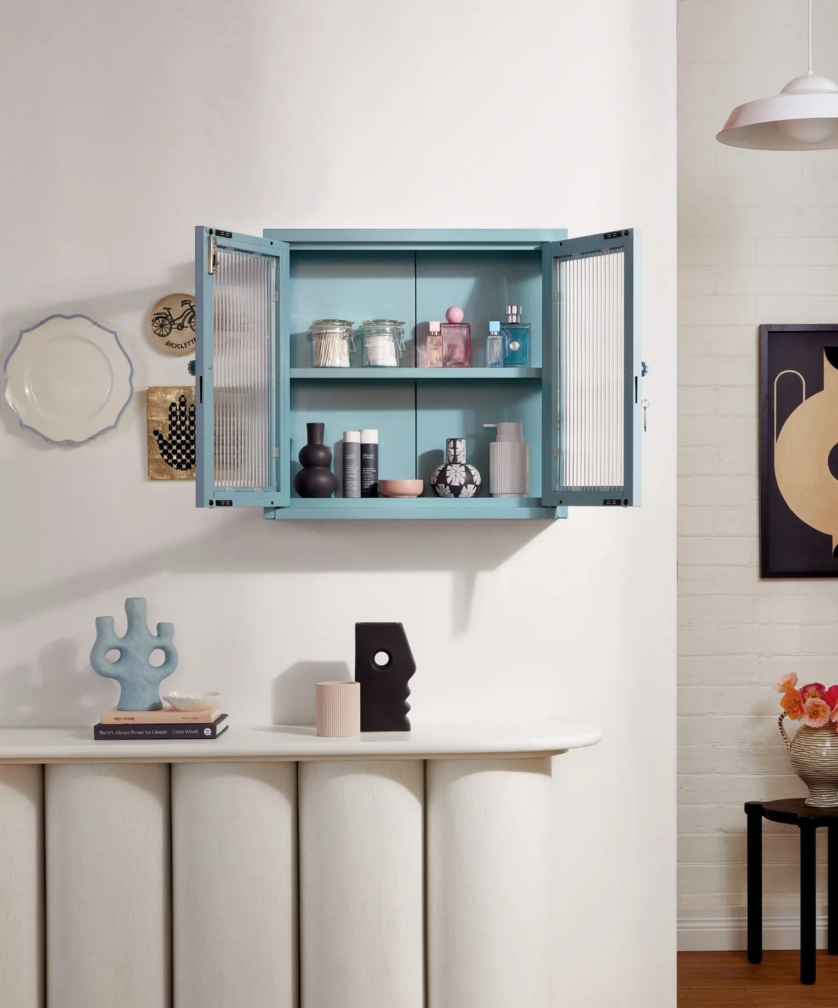 Blue wall cabinet with open doors displaying various items in a room setting.