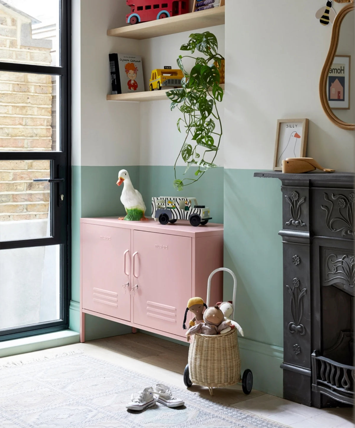 Children's corner in a room with a pink locker cabinet, toys, and a fireplace.