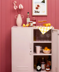 Pink cabinet with drinks and snacks against a pink wall