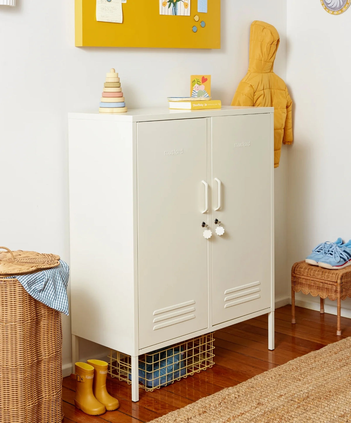 White locker cabinet with doors in a room with a yellow jacket, children's shoes, and toys.