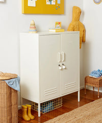 White locker cabinet with doors in a room with a yellow jacket, children's shoes, and toys.
