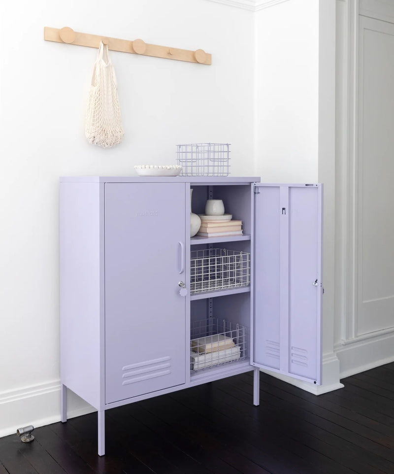 Purple storage cabinet with open door in a room with a white wall and dark wooden floor.