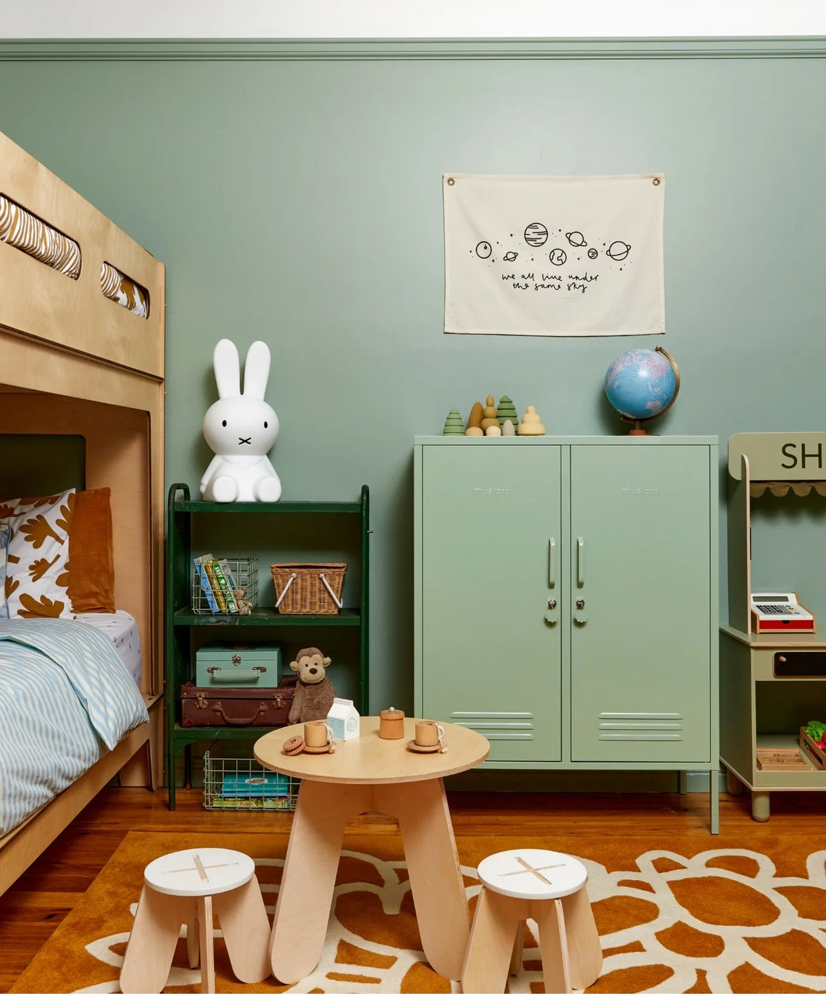 Children's room with green wall and locker, wooden furniture, and toys.