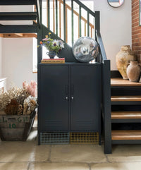 Dark Gray cabinet under a staircase with decorative items in a home setting