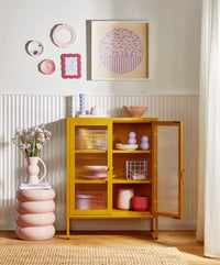 Yellow cabinet with open door in a room with decorative elements.