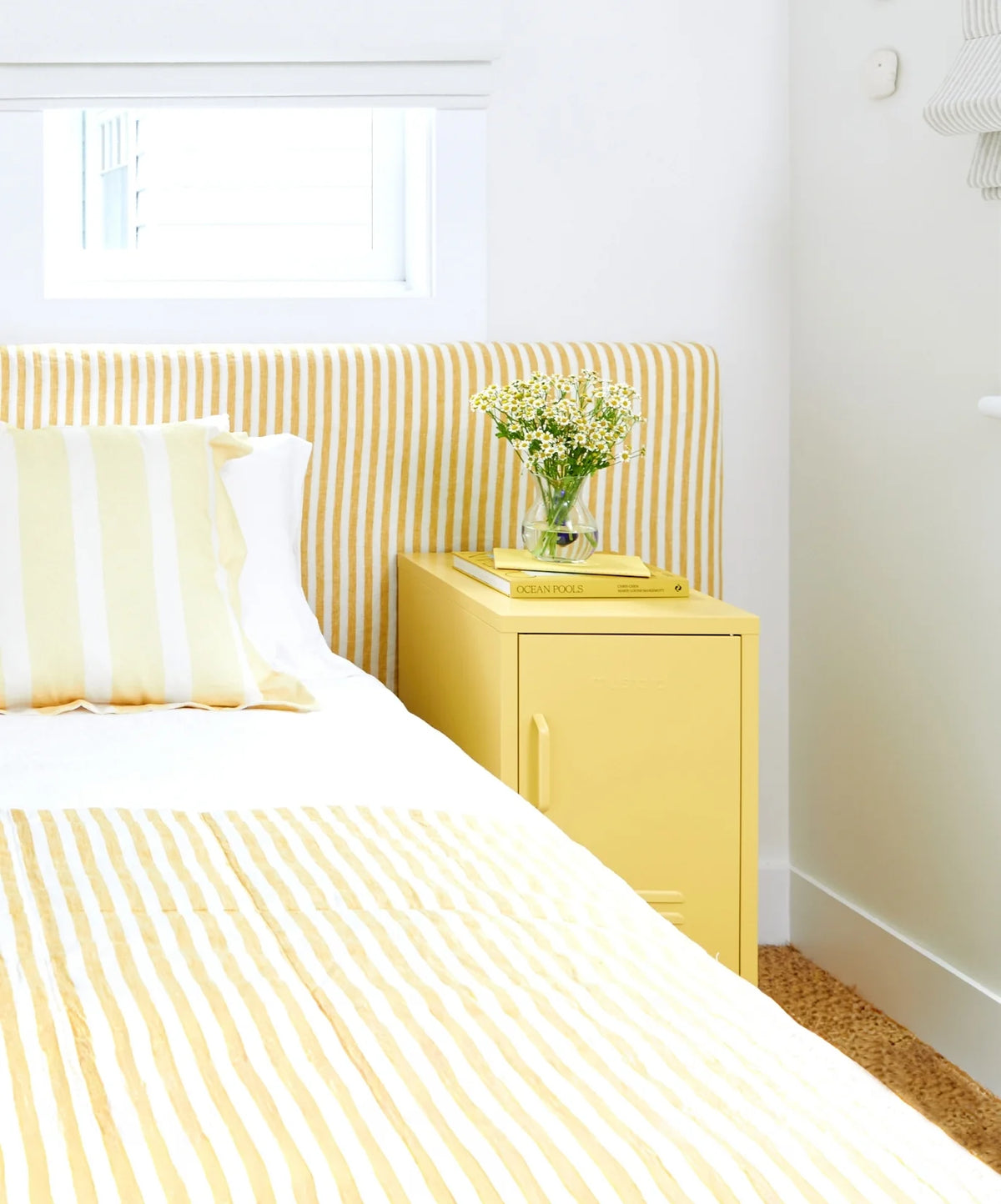 Bedroom with yellow striped headboard and matching locker nightstand.