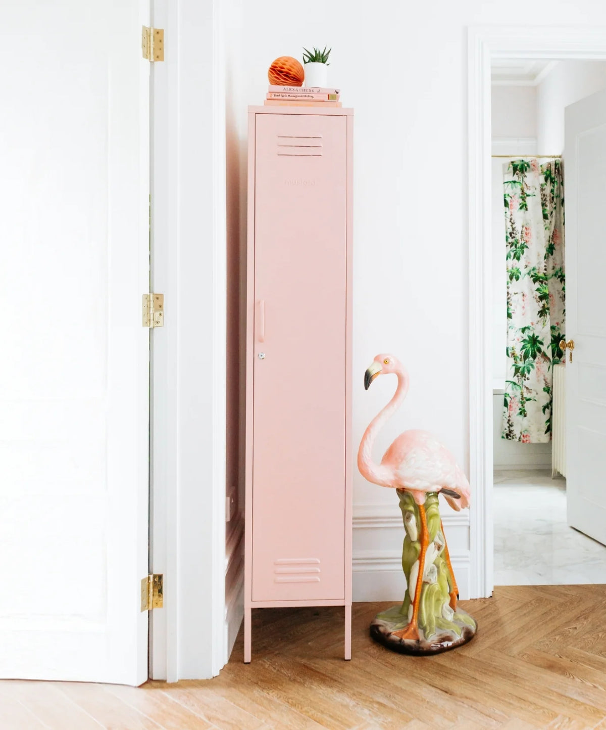 Pink locker with decorative flamingo figurine on a wooden floor.