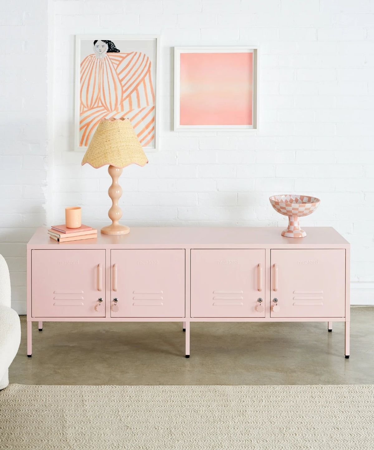Pink cabinet with decorative items in a room with abstract art on the wall.