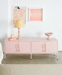 Pink cabinet with decorative items in a room with abstract art on the wall.