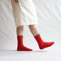 Person's legs wearing red socks and a white skirt on a white fabric background