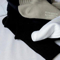 black white and beige cotton socks in a pile