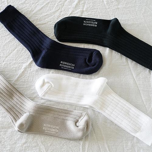 alternating socks in black, navy, white, and beige with NISHIGUCHI KUTSUSHITA logo printed on them