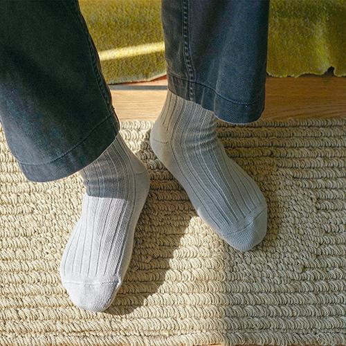 Person wearing light gray socks on a textured floor