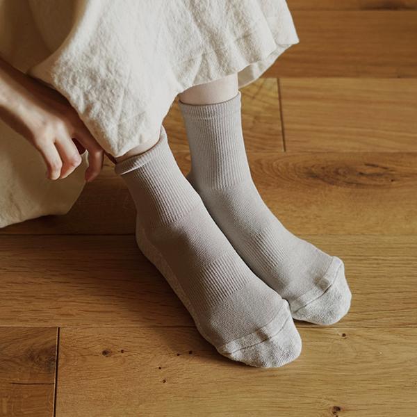 person wearing light grey ankle socks on a wooden floor