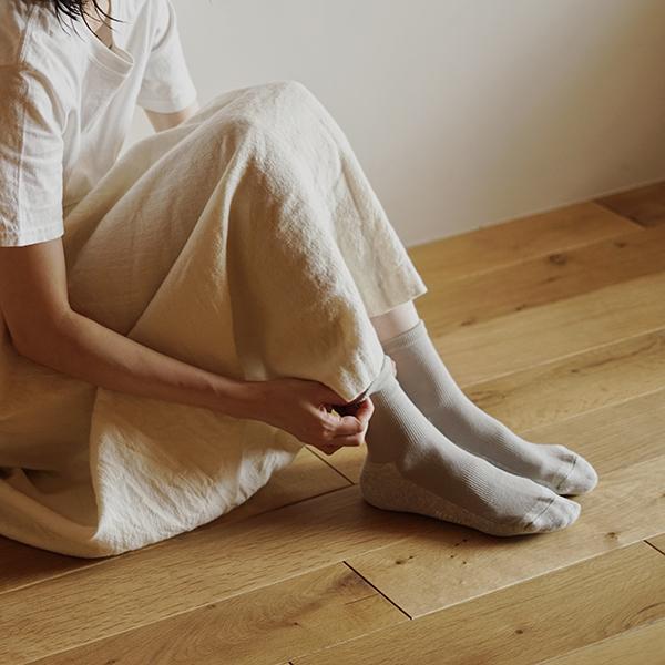 Person sitting on floor wearing a white dress and light grey socks