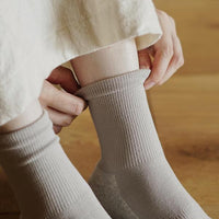 Close up of person putting on light grey ankle socks