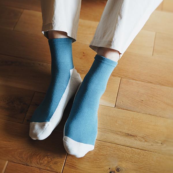 person wearing teal and white ankle socks on a wooden floor