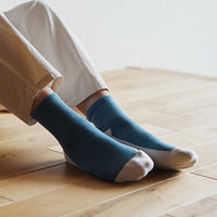 person wearing teal and white ankle socks on a wooden floor