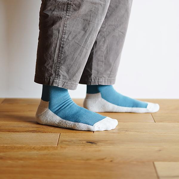 person standing on a wooden floor wearing teal and white socks and brown pants