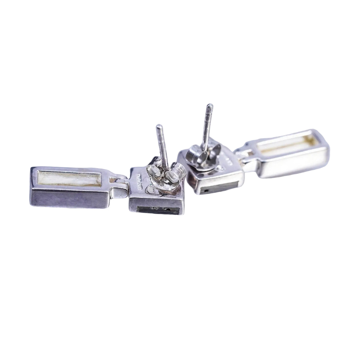 Backside of a pair of silver earrings on a white background