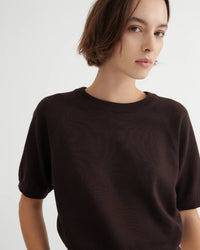 Woman wearing a dark brown short sleeve knit tee on a white background